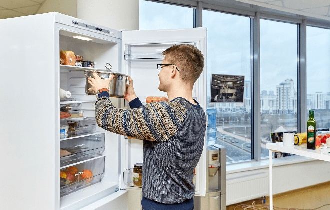 Чоловік ставить каструлю в холодильник